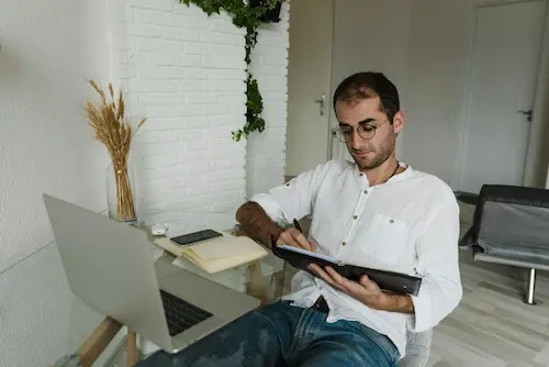 Homme travaillant à distance avec tablette et ordinateur.